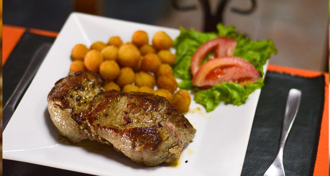 Entrecot a la plancha con papas noisette, lechuga y tomate en un plato blanco